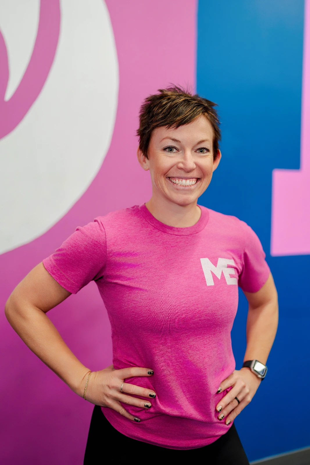 Megan Cooper, owner and head coach of Studio ME Fitness, standing with arms crossed and smiling in the Northeast Minneapolis studio.
